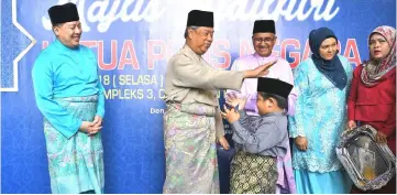  ??  ?? Muhyiddin (second left) kids around with Muhammad Danish Akram as the boy receives ‘duit raya’ from the minister. Looking on are Mohamad Fuzi (third right) and director of Bukit Aman CID director Datuk Seri Wan Ahmad Najmuddin Mohd (left).