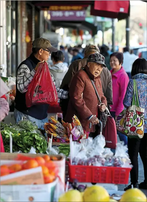  ?? JANE TYSKA — STAFF PHOTOGRAPH­ER ?? People shop in a market on Eighth Street in the bustling Chinatown neighborho­od of Oakland.