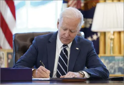  ?? PHOTOS BY ANDREW HARNIK — THE ASSOCIATED PRESS ?? President Joe Biden signs the American Rescue Plan, a coronaviru­s relief package, in the Oval Office of the White House in Washington on Thursday.