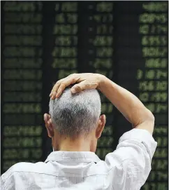  ?? GREG BAKER / AFP / GETTY IMAGES ?? A man checks stock price movements at a securities company in Beijing on Wednesday.