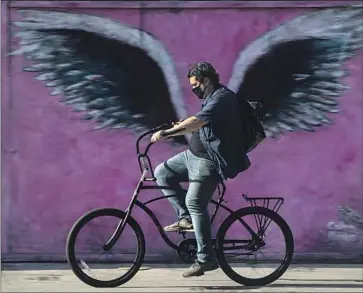  ?? Mel Melcon Los Angeles Times ?? A BICYCLE rider passes a mural on Melrose Avenue in Los Angeles. If the ballot measure making streets safer for pedestrian­s and cyclists is approved, it would let any resident sue the city if it failed to comply.