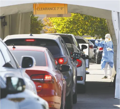  ?? COLE BURSTON / BLOOMBERG ?? A health-care worker gestures to waiting vehicles at a drive-through COVID-19 testing facility in Toronto Friday. A spokeswoma­n for Ontario’s health ministry said they are looking at allowing pharmacies to perform COVID testing.