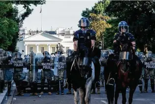  ?? Erin Schaff / New York Times ?? Police in riot gear advance on protesters, clearing a path so Donald Trump can walk from the White House, visible in the background, to St. John’s church in Washington on June 1.