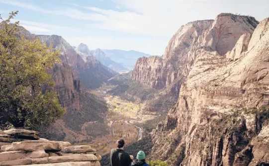  ?? NIKKI BOLIAUX/THE NEW YORK TIMES PHOTOS ?? Hikers take in the view Nov. 23 from the summit of the Angels Landing trail in Zion National Park in Utah, where the number of visitors has surged.