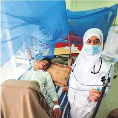  ?? Reuters ?? ■
A patient, suffering from dengue fever, receives medical aid as he lies under a mosquito net inside a dengue ward at Lady Reading Hospital in Peshawar.