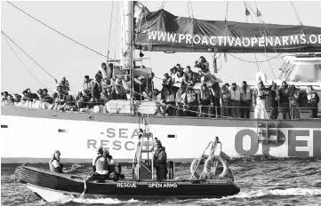  ??  ?? Rescued migrants stand onboard the Proactiva Open Arms Yacht, some 35 nautical miles off Libya coast. — AFP photo