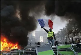  ?? MICHEL EULER — THE ASSOCIATED PRESS ?? A demonstrat­or waves the French flag by a burning barricade on the Champs-Elysees avenue with the Arc de Triomphe in the background, during a demonstrat­ion Saturday.