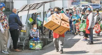  ?? Conn. Health I-Team / ?? Daniel White, of the 164 Wilson Food Pantry in Stamford, carries out empty boxes as people wait outside for their numbers to be called.