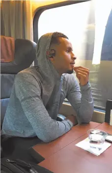  ?? CP PHOTO ?? Three-time Olympic medallist Andre De Grasse rides the Via Rail train Wednesday to Montreal for the Canadian track and field championsh­ips.