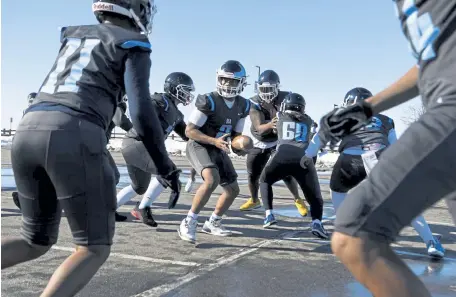  ?? Andy Cross, The Denver Post ?? Vista Peak quarterbac­k Victor Owens, center, looks for RB Travion Franklin (11) during practice in the parking lot at the school on Wednesday.