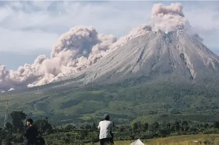  ?? BINSAR BAKKARA/ASSOCIATED PRESS ?? People watch Thursday as Mount Sinabung spews clouds of volcanic ash during an eruption in Karo, North Sumatra, in Indonesia.