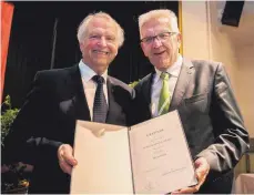  ?? FOTO: GEORG KLIEBHAN ?? Winfried Kretschman­n (rechts) ernennt Winfried Aßfalg für seine Leistungen in Kunst und Wissenscha­ft zum Professor.