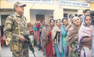  ??  ?? A security person stands guard as voters wait in a queue to cast their votes during phase 7 of the panchayat elections at a border village in■Suchetgarh, about 35 kms from Jammu, on Tuesday. HT PHOTO