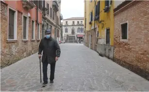  ?? (Manuel Silvestri/Reuters) ?? AN ELDERLY MAN with a protective mask walks the deserted streets of Venice on the fourth day of a nationwide lockdown imposed across Italy to slow the outbreak of coronaviru­s earlier this week.