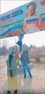  ?? ?? EMOCIÓN. Los pobladores reciben a los soldados e izan banderas. Y retiran el cartel que reza: “Rusia estará aquí para siempre”.
