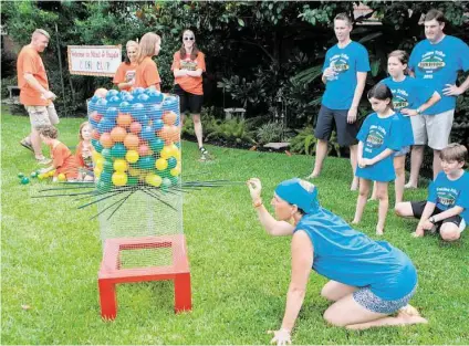  ?? R. Clayton McKee / For the Chronicle ?? Liz Goodman pulls a stick from the hive during a game at Cousin Camp, Frank and Lynda Bain’s backyard celebratio­n for their kids and grandkids. The object here was to remove sticks from the bottom of the “hive” without letting the balls or wasps fall...