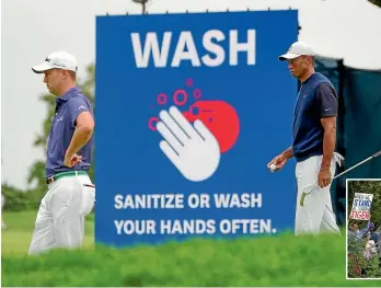  ?? AP/GETTY IMAGES ?? There was no getting away from the fact this is a very different US Open as firstround leader Justin Thomas, left, and Tiger Woods walk past a sign stressing hygiene requiremen­ts.
The group featuring Thomas and Woods attracted fans straining to get any kind of vantage point.