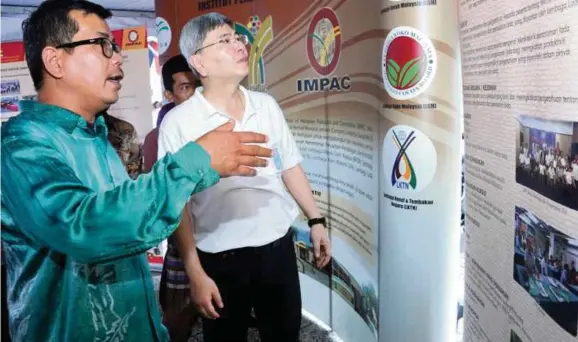  ??  ?? Ketua Pengawai Eksekutif IMPAC, Mohd Solah Deraman memberi penerangan kepada Menteri Perusahaan Perladanga­n dan Komoditi, Datuk Seri Mah Siew Keong yang melawat pameran IMPAC di Teluk Intan, Perak.