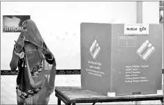  ??  ?? A woman covers her face as she leaves a polling booth after casting her vote during the first phase of state assembly election in Limbdi town of Surendrana­gar district in the western state of Gujarat, India. — Reuters photos