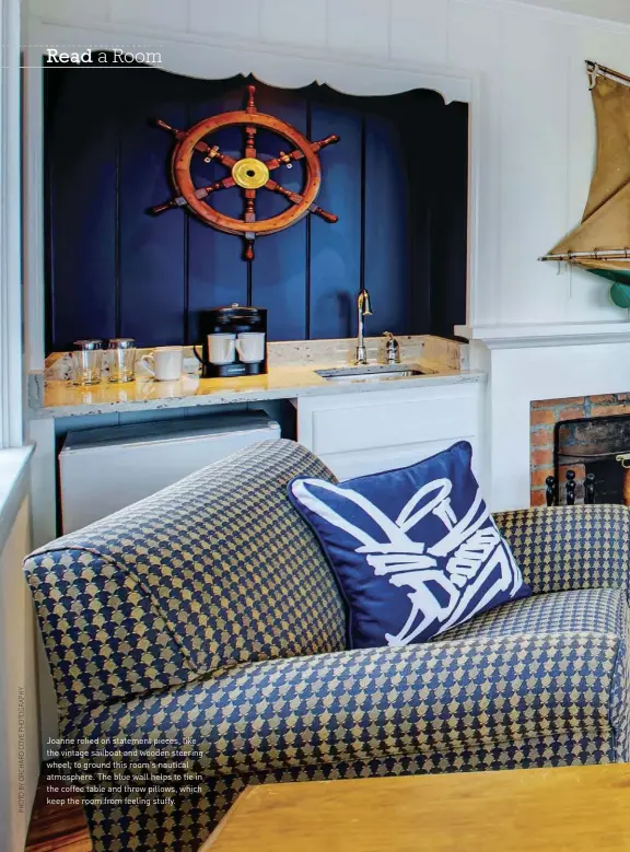  ??  ?? Joanne relied on statement pieces, like the vintage sailboat and wooden steering wheel, to ground this room's nautical atmosphere. The blue wall helps to tie in the coffee table and throw pillows, which keep the room from feeling stuffy.