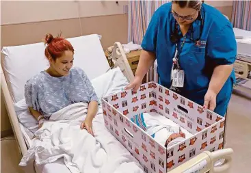  ?? Matt Rourke / Associated Press ?? Keyshla Rivera smiles at her newborn son, Jesus, as registered nurse Christine Weick demonstrat­es a baby box Friday at Temple University Hospital in Philadelph­ia. The city has an infant mortality rate nearly double the U.S. average, so Temple is...