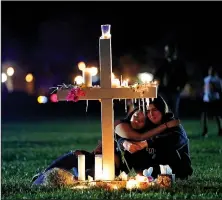  ?? The Associated Press/GERALD HERBERT ?? Two people comfort each other Feb. 15 as they sit and mourn at one of 17 crosses after a candleligh­t vigil for the victims of the shooting at Marjory Stoneman Douglas High School, in Parkland, Fla. Arkansas faith leaders called for prayers, action and...