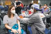  ?? Marta Lavandier Associated Press ?? NATALIA DUBOM receives a COVID-19 vaccine at Miami Internatio­nal Airport on Friday.