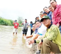  ??  ?? Kennedy (seated, third from right), Edwin (second right) and other villagers releasing the fish fry into the Pegalan River.