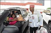  ??  ?? Robert Wright, who’s been on the Varsity staff for 30 years, delivers a takeout order to regular customer Beulah Walker of Atlanta at the Varsity in Midtown Atlanta on Aug. 2.