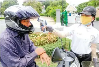  ?? HENG CHIVOAN ?? A security guard checks a man’s temperatur­e before he enters a Phnom Penh hotel. The health ministry has renewed its calls for the public to follow strict hygiene practices.