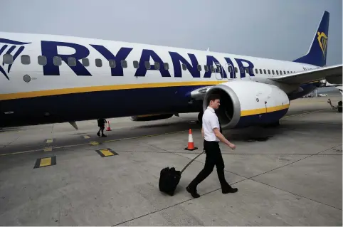  ?? (Clodagh Kilcoyne/Reuters) ?? A PILOT DISEMBARKS a Ryanair flight at Stansted airport in London earlier this year.