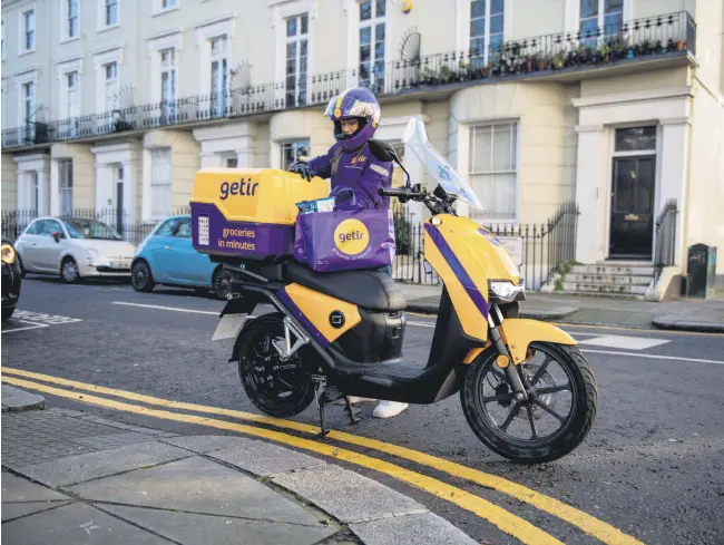  ??  ?? A Getir courier is seen beside his bike, London, U.K., Jan. 27, 2021.