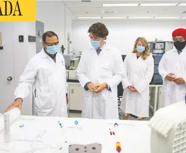  ?? REUTERS/FILES ?? Prime Minister Justin Trudeau, with Economic Developmen­t Minister Mélanie Joly and Innovation, Science and
Industry Minister Navdeep Bains, speaks with Krishnaraj Tiwari about vaccines at NRCAN in Montreal.