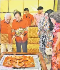  ??  ?? TERTARIK: Wong (dua kiri) menerangka­n sesuatu berkenaan dengan keunikan ‘Nian Gao’ (kek pulut) kepada Tun Taib semasa kunjungan Tahun Baharu Cina ke kediamanny­a di Sibu, semalam.