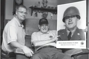  ?? Associated Press ?? Kokomo, Ind., resident Frank Merrill, center, holds up a photo of himself when he served in the Army during the Korean War. Merrill, accompanie­d by his son Scott, left, recently went on an Honor Flight to Washington, D.C., to visit military monuments...