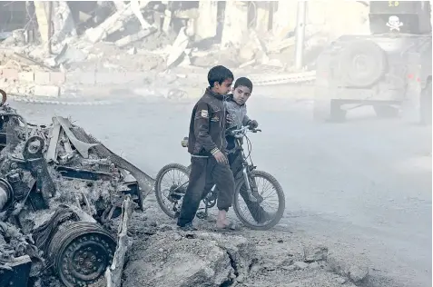  ??  ?? Boys play by a destroyed Humvee in Sammod, on the south-west edge of Mosul. It and other areas recaptured from Isil face severe shortages of water, fuel and electricit­y