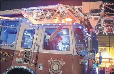  ?? ROBERTO E. ROSALES/JOURNAL ?? Firefighte­r Eric Adair waves to the crowd after he treated a young girl who was choking on a candy cane during the Twinkle Light Parade earlier this month.