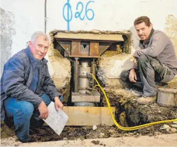  ?? FOTO: DIERKING ?? Mit Hilfe einer Hydraulik werden die Pfähle in den Boden gepresst: Verantwort­lich für die Bauarbeite­n sind Ingenieur Paul Landthaler (links) und Franz-Josef Kühn.