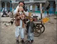  ?? ?? A fruit seller lifts his son by his cheeks March 12, 2014, in the center of Kandahar, Afghanista­n.