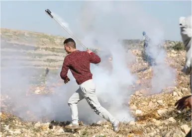  ?? (Reuters) ?? A PALESTINIA­N protester prepares to hurl a stone.