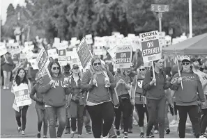  ??  ?? Striking teachers carry picket signs as they march around the Tacoma School District Central Administra­tion Building on Monday in Tacoma, Wash. AP