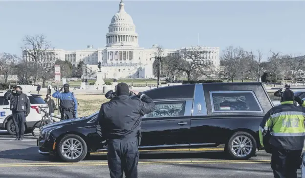  ??  ?? 0 US Capitol police stand at attention as the hearse carrying fallen police officer, Brian Sicknick, passes during a funeral procession in Washington yesterday
