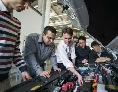  ?? NSERC/UNIVERSITY OF WATERLOO ?? Professor John McPhee, centre, reviews wiring configurat­ion with graduate student researcher­s at the University of Waterloo.