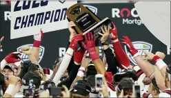  ?? CARLOS OSORIO — THE ASSOCIATED PRESS ?? Ball State players reach for the trophy after defeating Buffalo in the MidAmerica­n Conference championsh­ip on Friday in Detroit.