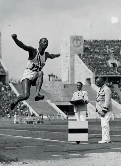  ??  ?? O atleta negro norte-americano Jesse Owens voa para mais uma medalha de ouro nas Olimpíadas de Berlim, em 1936. Owens conquistar­ia quatro medalhas de ouro durante os Jogos, causando incómodo e embaraço ao regime de Adolf Hitler, agravado pela transmissã­o televisiva da competição.