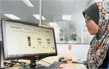  ??  ?? Online shopping: A Foodmarket employee busy keying in the orders from customers. In Malaysia online shopping is still emerging as mainstream behaviour.