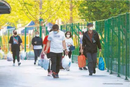  ?? ?? Residents return from the supermarke­t with full bags. — Zhou Shengjie