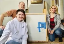  ?? COURTESY OF SCOTT GARNER ?? Scott and Angela Garner, along with their son, Reed, pose with a painting Keith Haring painted on a wall in his childhood home. The Garners, who now own the house, are auctioning off the artwork.