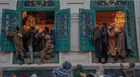  ??  ?? Kashmiri Muslim devotees watch from the window as the head priest displays a relic of Sufi saint Syed Abdul Qadir Gilani at his shrine in Srinagar, Indian-controlled Kashmir