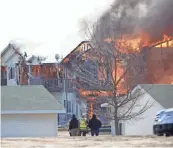  ?? DOUG RAFLIK/USA TODAY NETWORK-WISCONSIN ?? Firefighte­rs and others watch Village Glen Apartments' Building 109 during a controlled burn on Thursday.